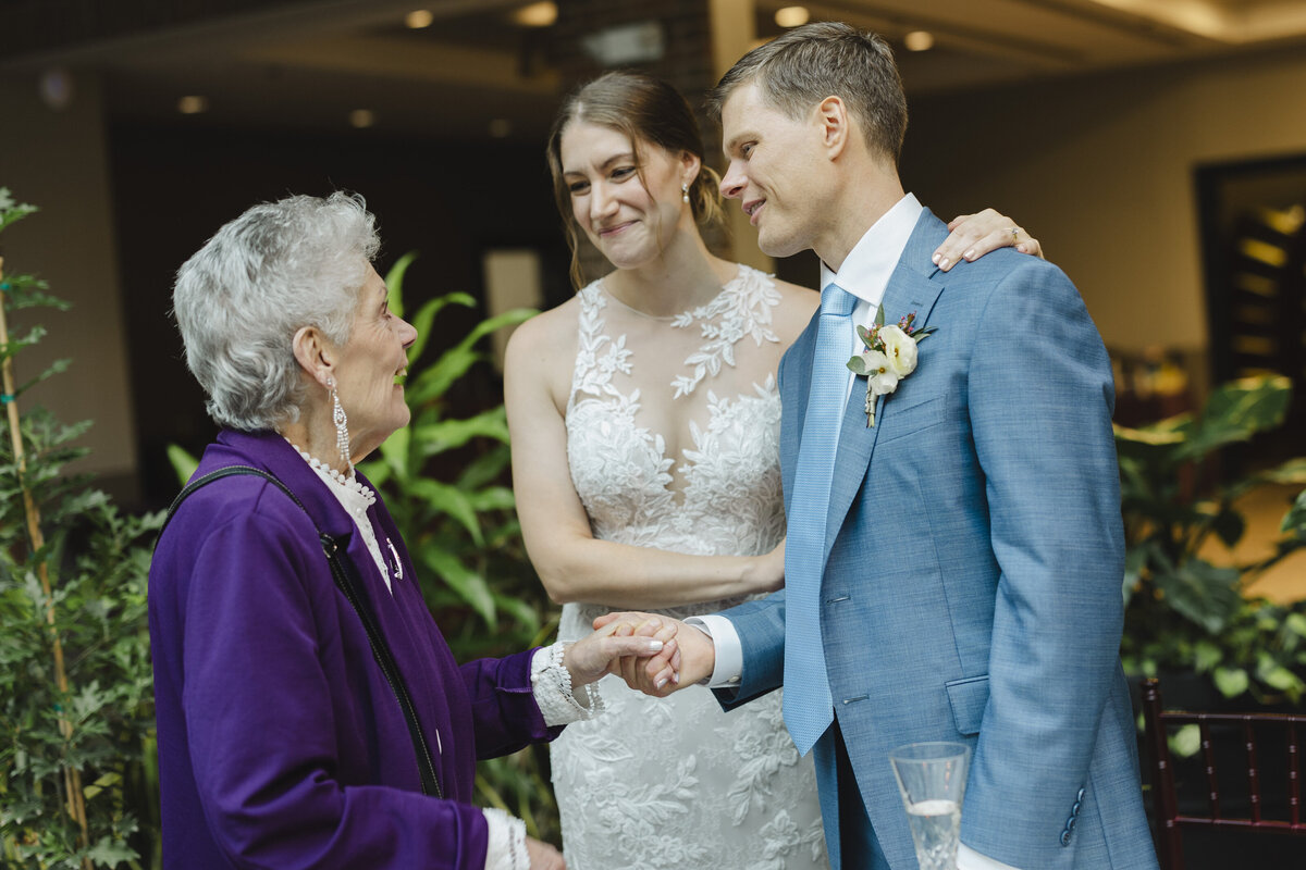 An older women smiling and talking to a newlywed couple 