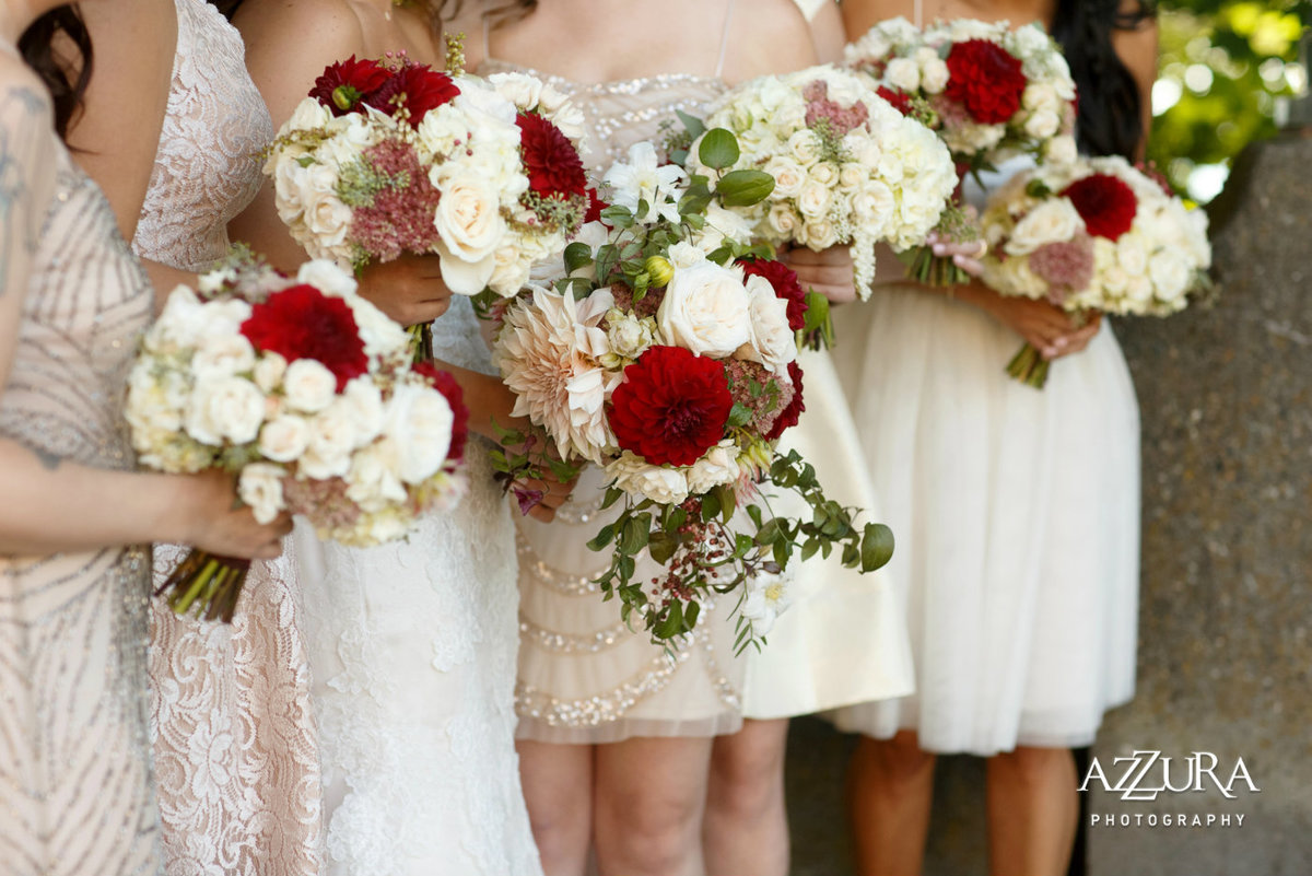 white and red bridal bouquets with red dahlias, white roses, and trailing greenery
