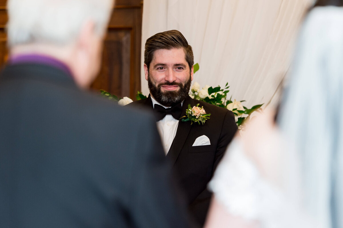a closeup of the grooms emotional face as he sees his bride coming up the aisle during his Chateaul Laurier wedding ceremony.  Captured by Ottawa wedding photographer JEMMAN Photography