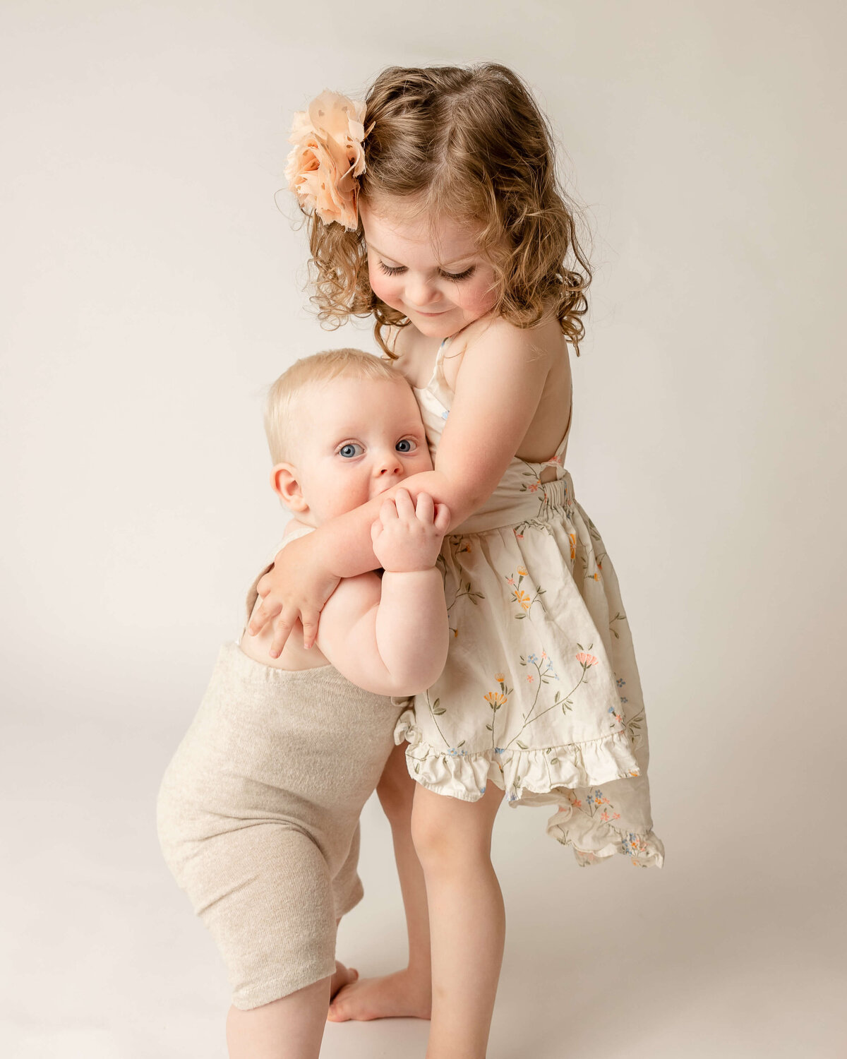 adorable photo of three year old sister helping six month old brother stand up