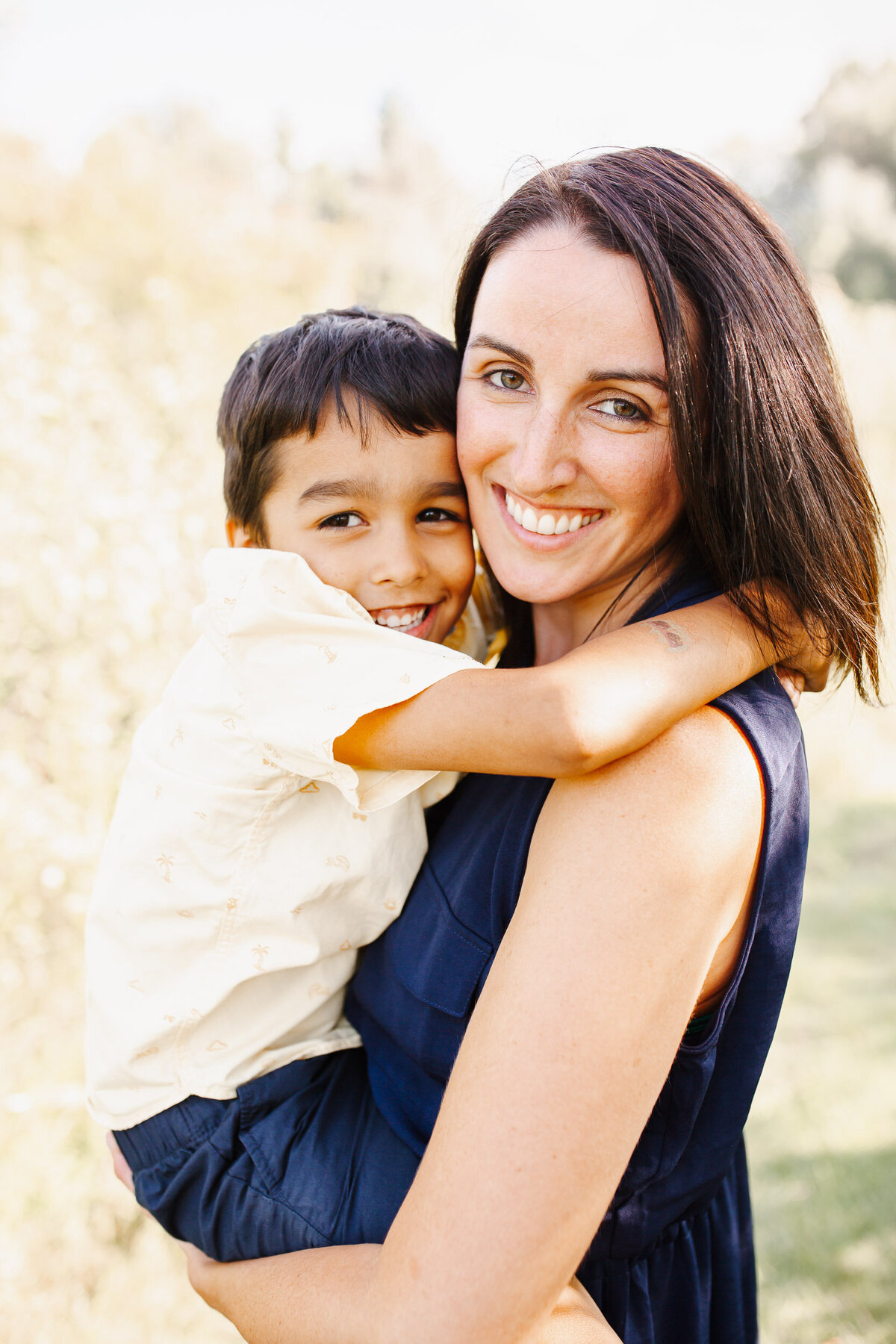 Little boy in yellow hugs his Mom.