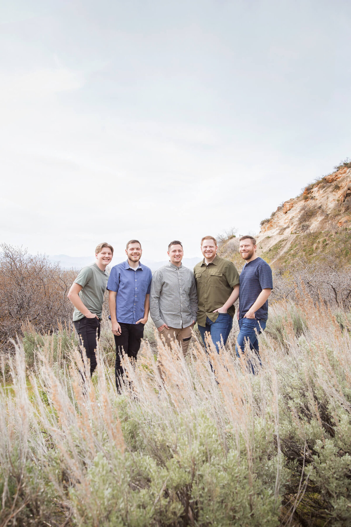 adult brothers standing next to each other on a mountain behind sage brush