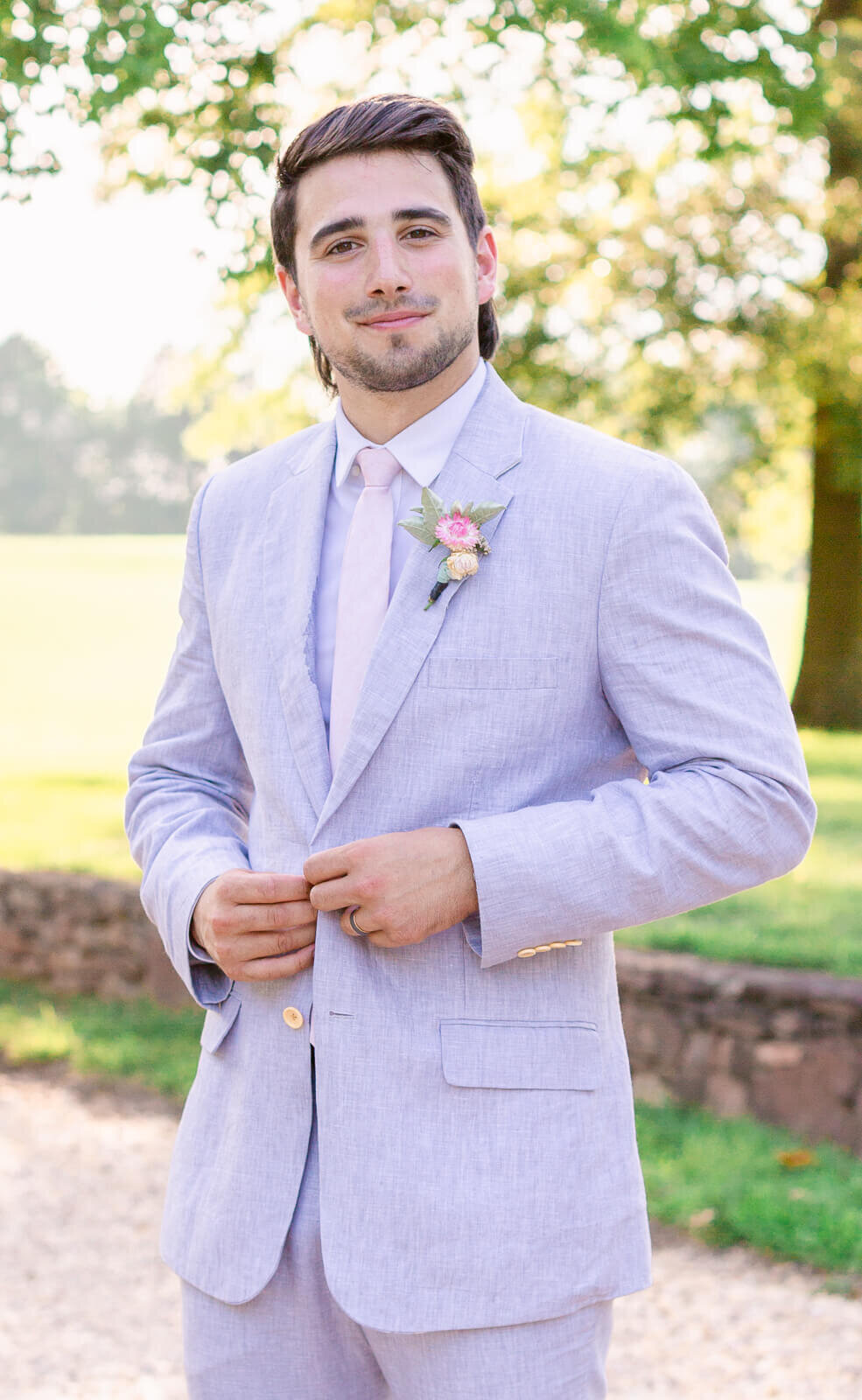 Groom buttoning suit jacket during getting ready photos at Great Marsh Estate. Captured by Bethany Aubre Photography.