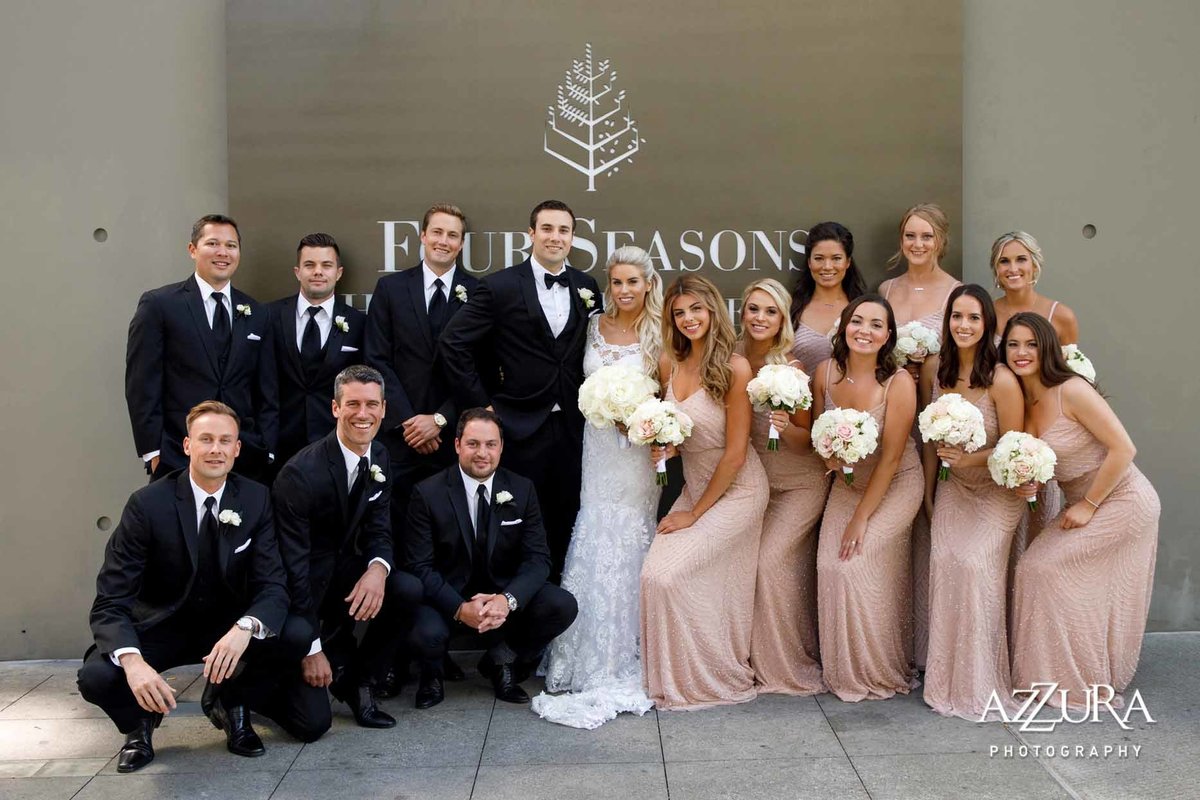Beautiful wedding party with white rose bouquets, wearing long blush dresses in front of Four Seasons Hotel Seattle