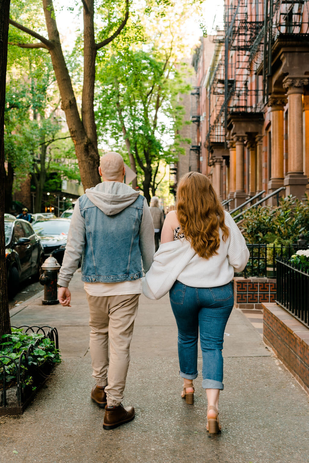 couple holding hands and walking down a sidewalk