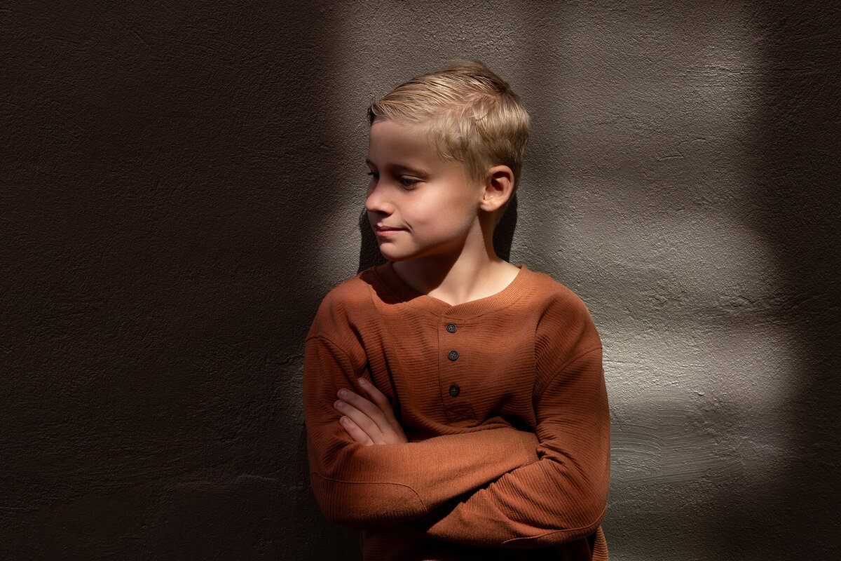 A child's face, illuminated by a single sunbeam in a shadowy alley.
