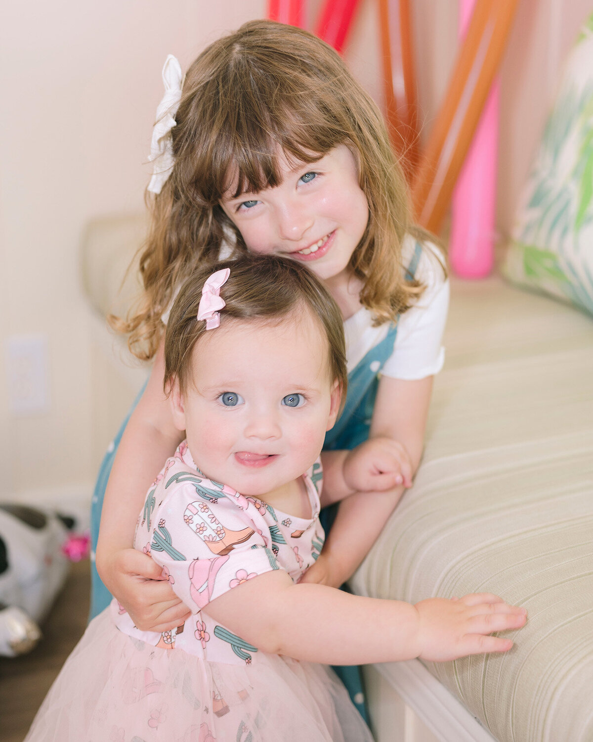 Big sister hugging baby girl at her first birthday party in the San Francisco Bay Area, captured by a first birthday party photographer.

