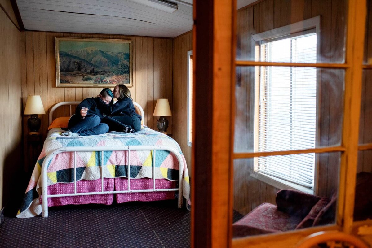 a same sex couple hugs while sitting on a colorful bed