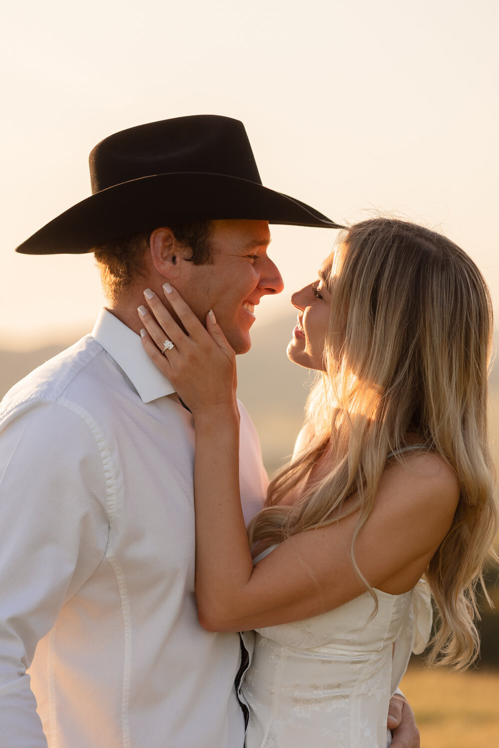 Candid couple during engagement photos in golden hour field with hills in San Luis Obispo 
