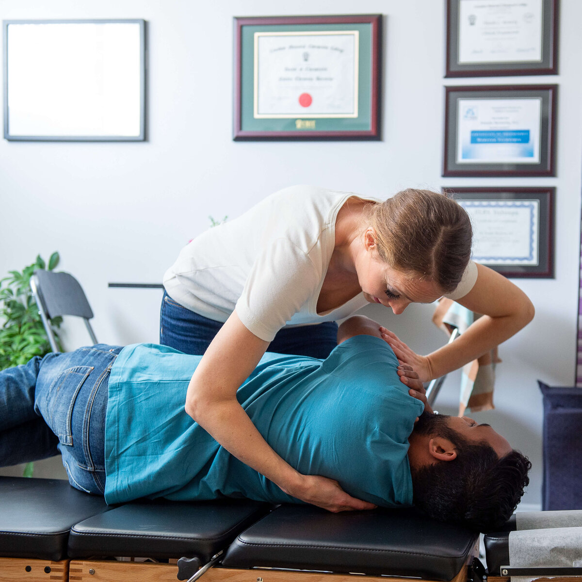 a female chiropractor adjusts a male patients spine and shoulder.  Capture on location by Ottawa Brand Photographer JEMMAN Photography Commercial