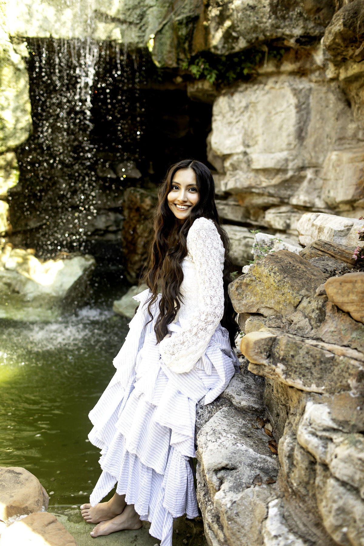 Captured in the warmth of the sun, a high school senior poses amidst the vibrant flowers and greenery of Chandor Gardens, marking a new beginning in her life