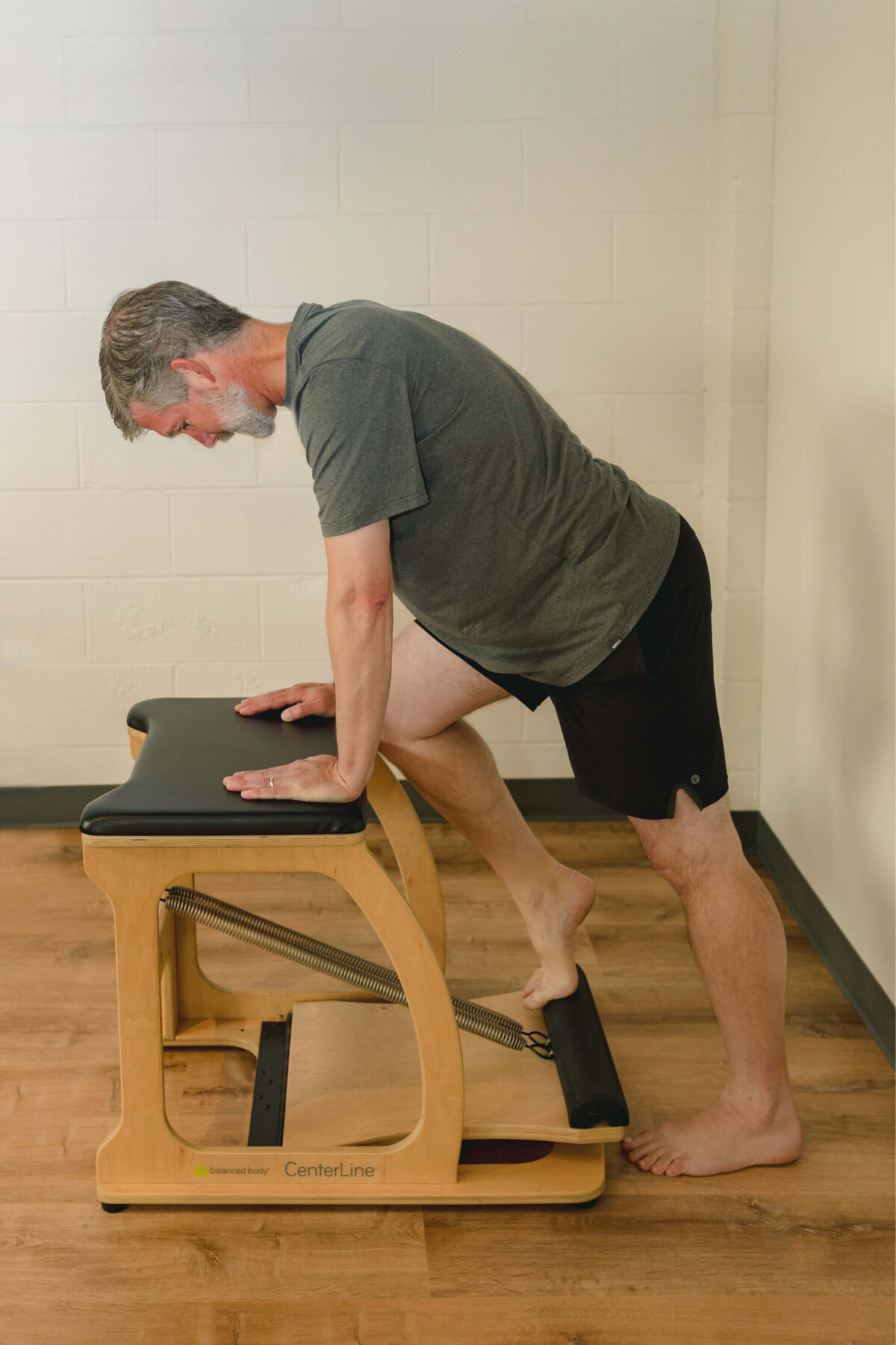 Man practicing foot ankle Pilates exercise on chair