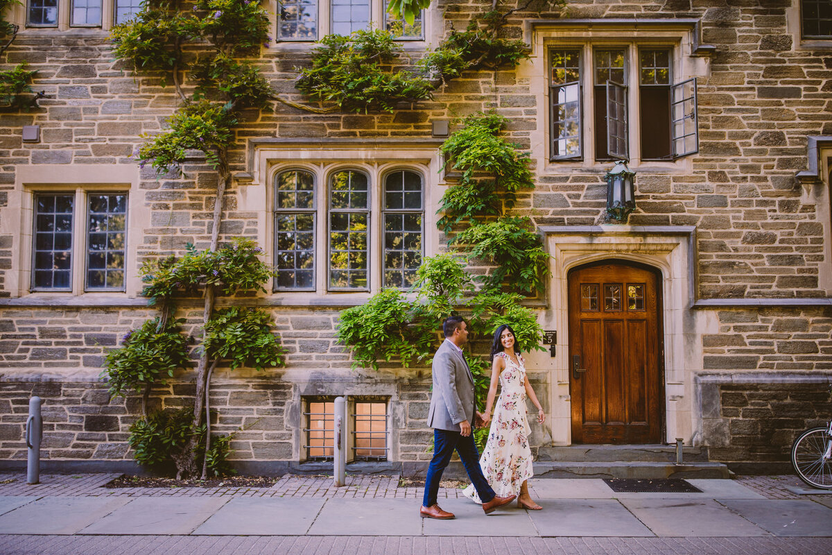 engaged couple walk with the princeton university buildings in the background in nj