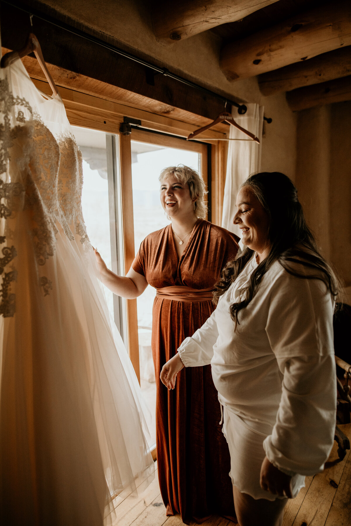 bride and bridesmaid admiring bridal gown