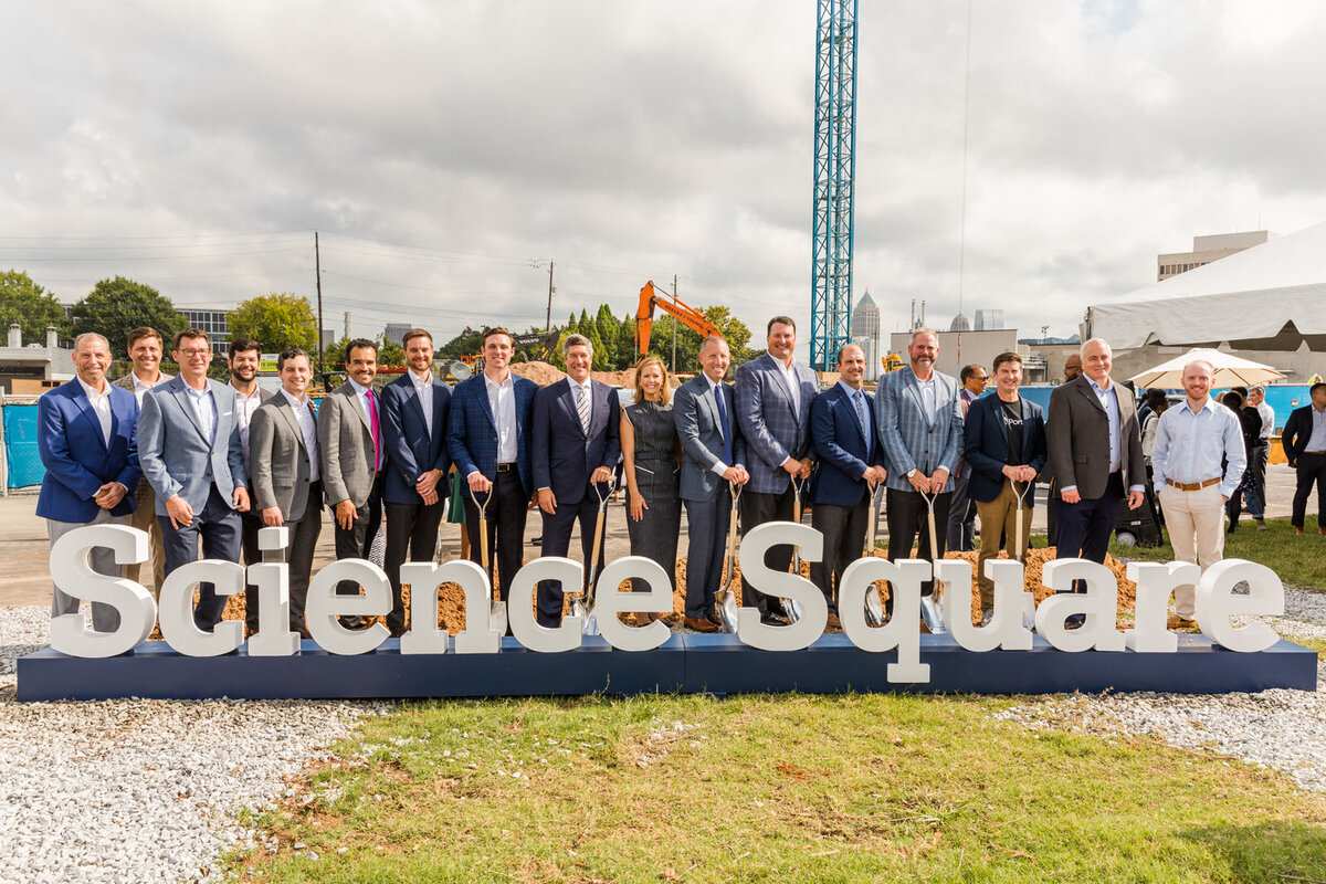 team standing behind a sign with shovels for a ground breaking ceremony in Atlanta with Laure Photography