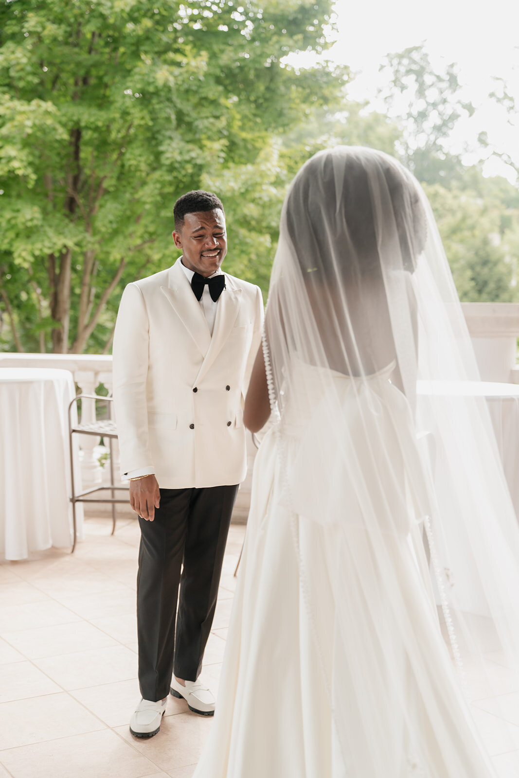 black groom admiring black bride in wedding gown with long veil