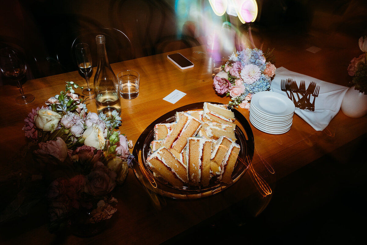 Direct flash photo late at night with wedding cake and floral decor. Taken at Poachers Pantry by Acacia and Grace Photography, a Canberra wedding photographer