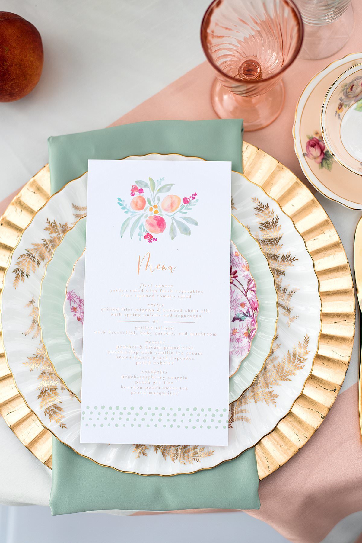 table place setting with a gold charger, teal napkin, vintage china dinner plate, vintage china salad plate, vintage china dessert plate and floral menu card