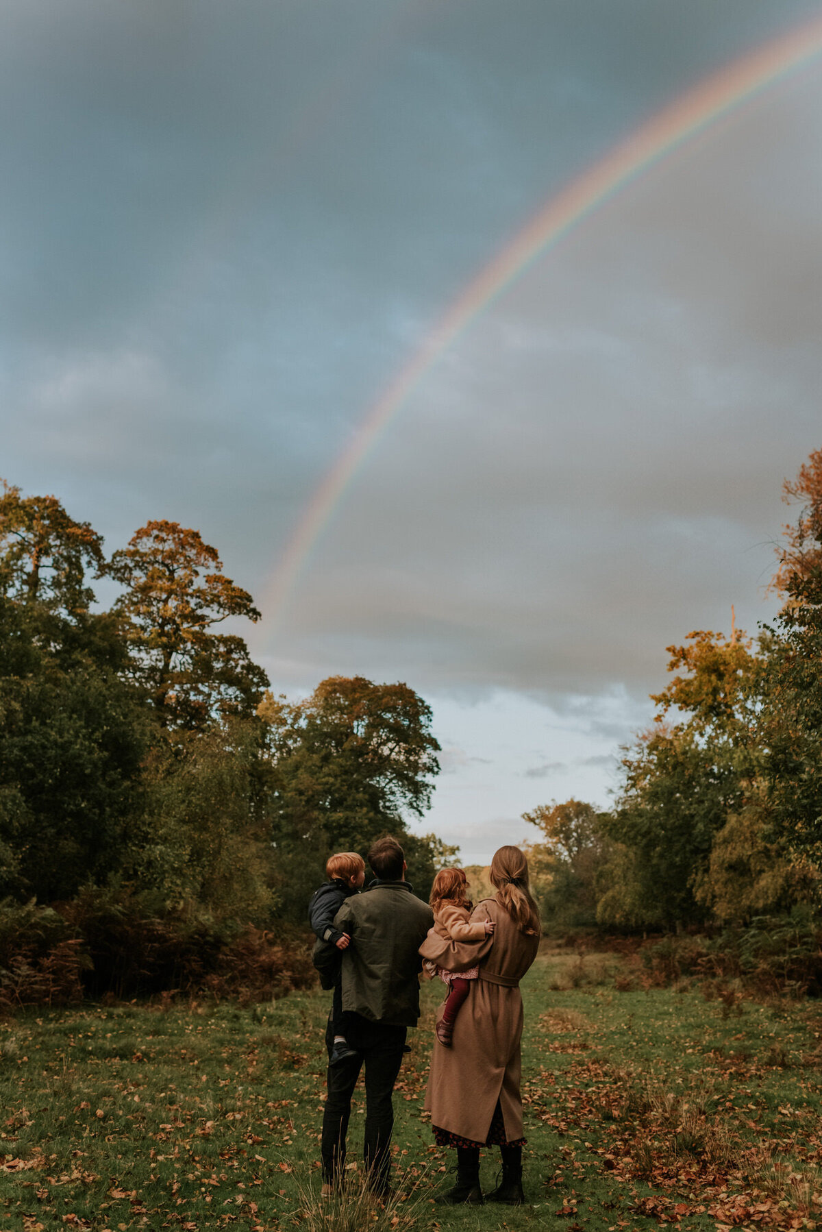Family holding young children and watching rainbow