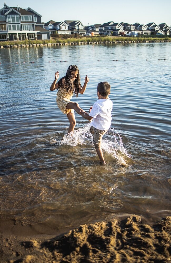 Little boy and girl running and splashing in a lake near Edmonton
