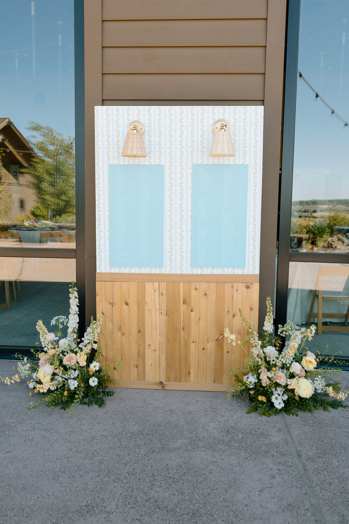 Seating chart wall with wedding calligraphy details featuring florals, wood accents and floral wallpaper representing full service design and calligraphy by Life in Letters.