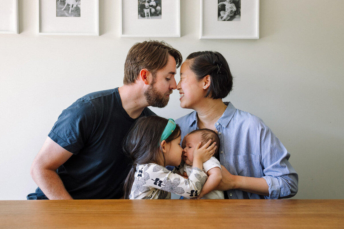 mom and dad touching noses with daughter and baby sitting in front touching noses
