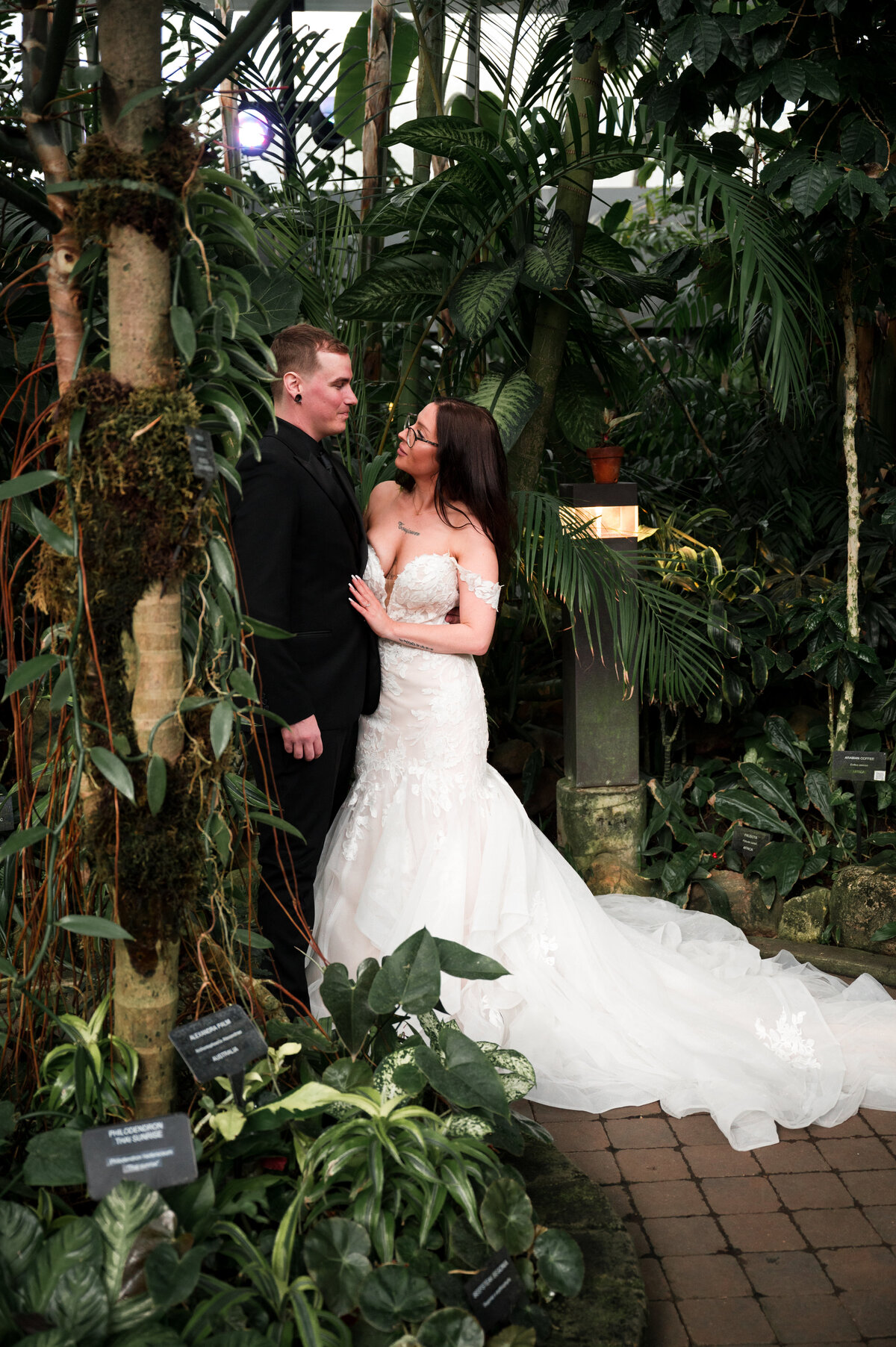 bride and groom amongst tropical plants looking into each others eyes