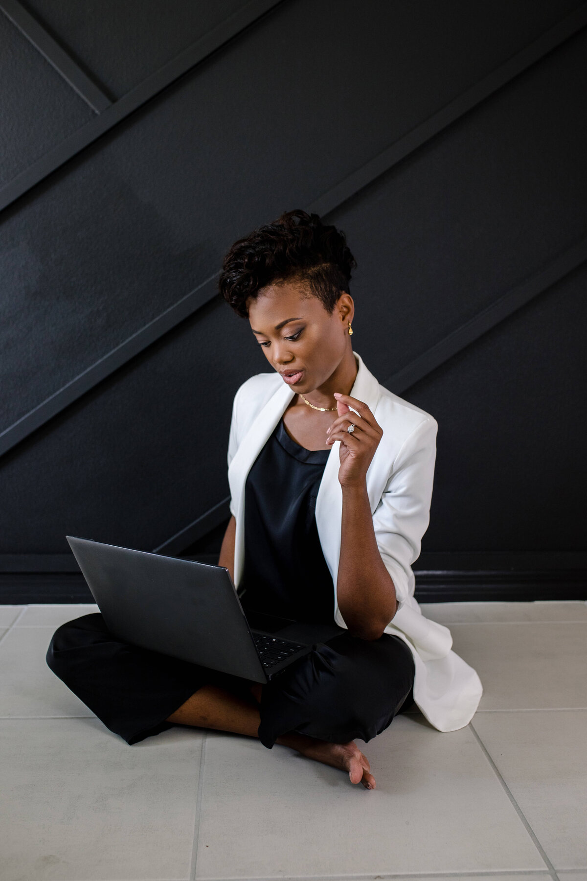 Brand photography with woman sitting on the floor crosslegged with her laptop on her lap as she poses for a branding photo shoot