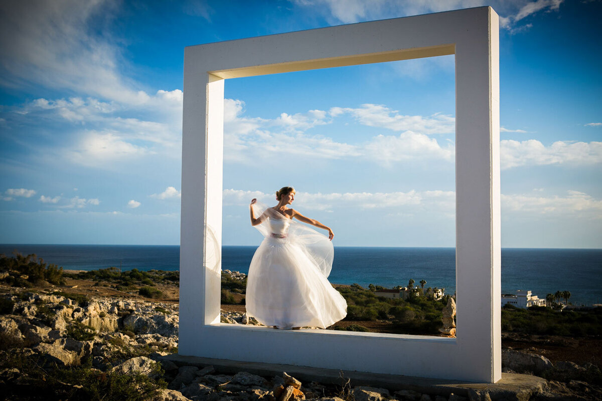 Bride standing high on a hill overlooking the sea
