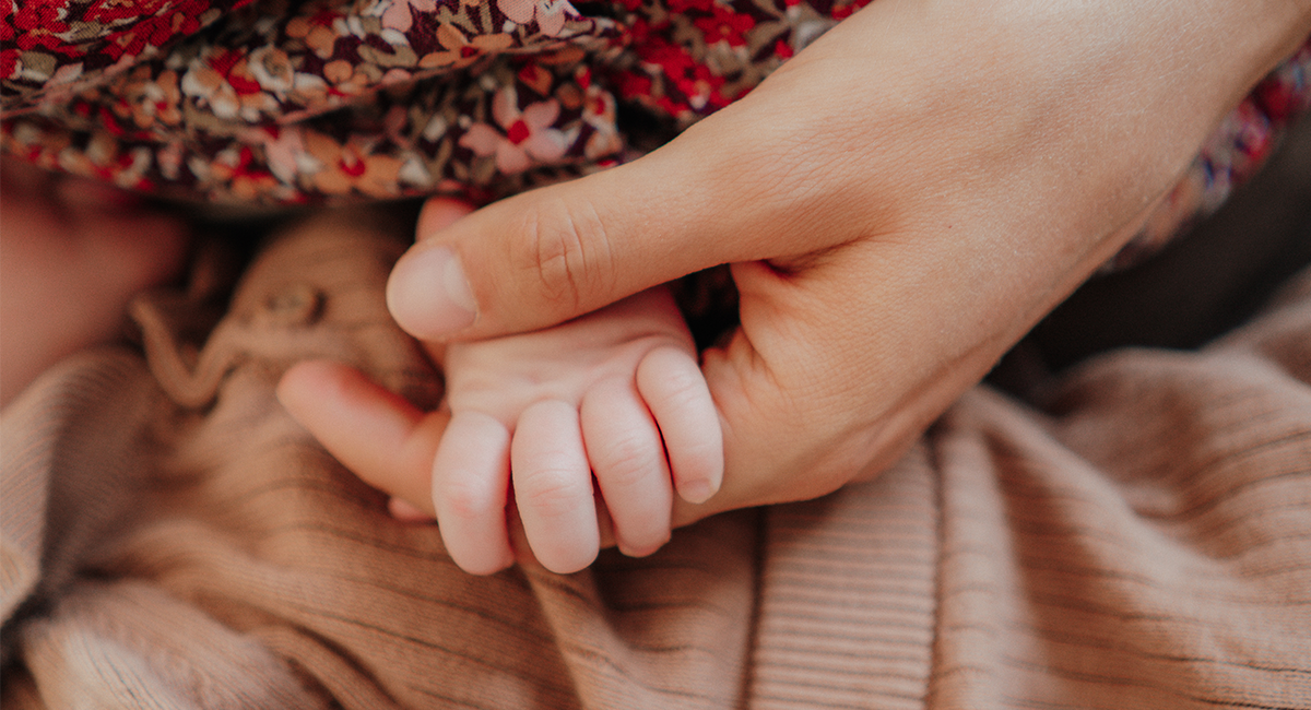 Das Baby umgreift mit seiner Hand Mamas Zeigefinger