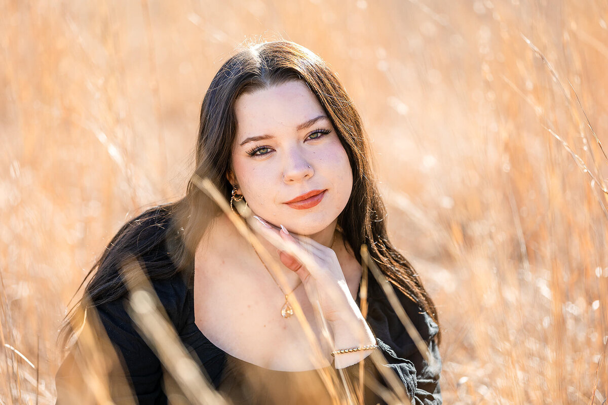 Beautiful sunlit grasses frame the face of a senior girl in Minnesota.