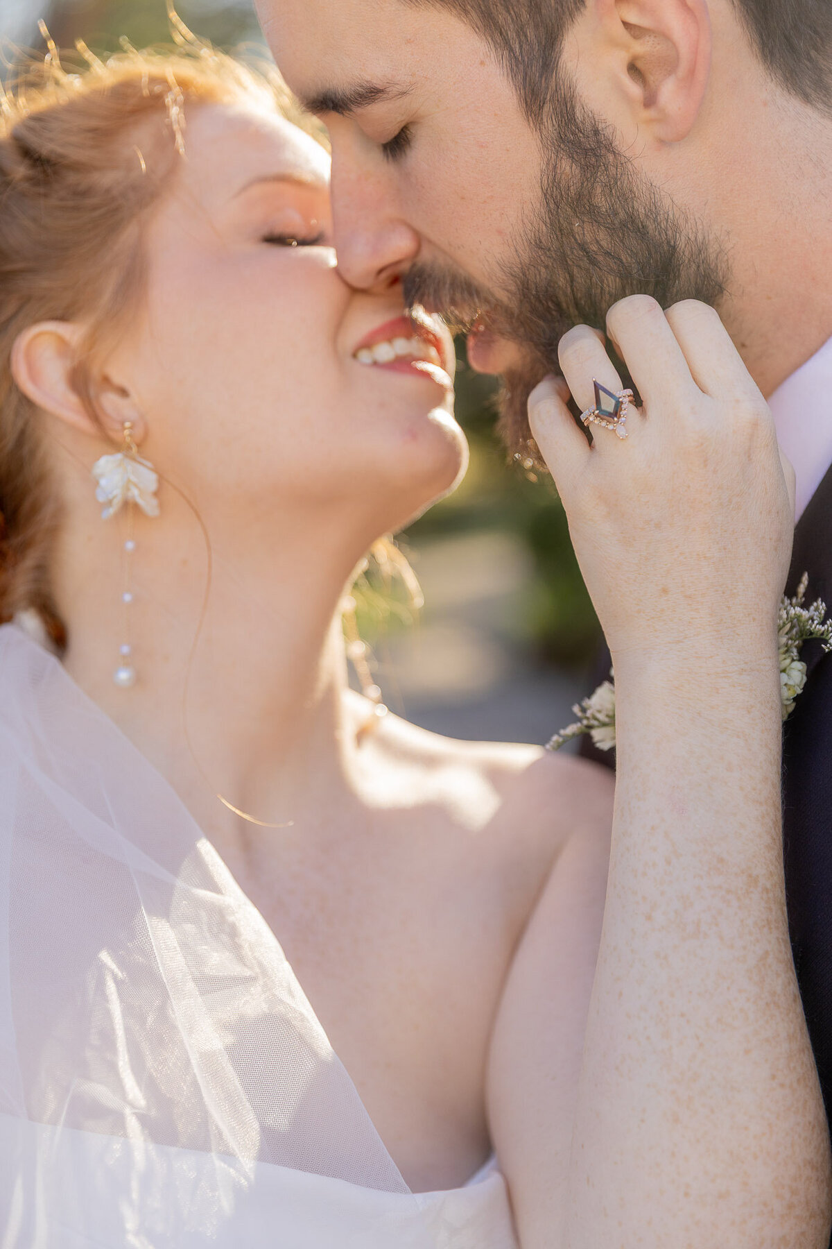 Close up of a bride and groom about to kiss on their wedding day. The photo highlights her wedding ring.