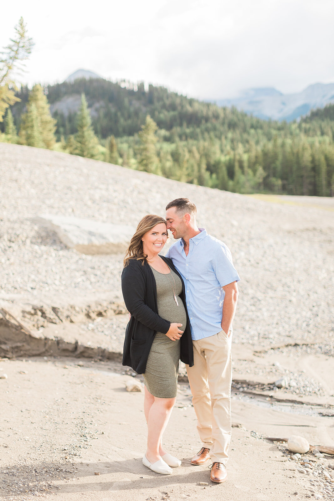 Pregnant woman smiling and holding her baby bump while man smiles next to her