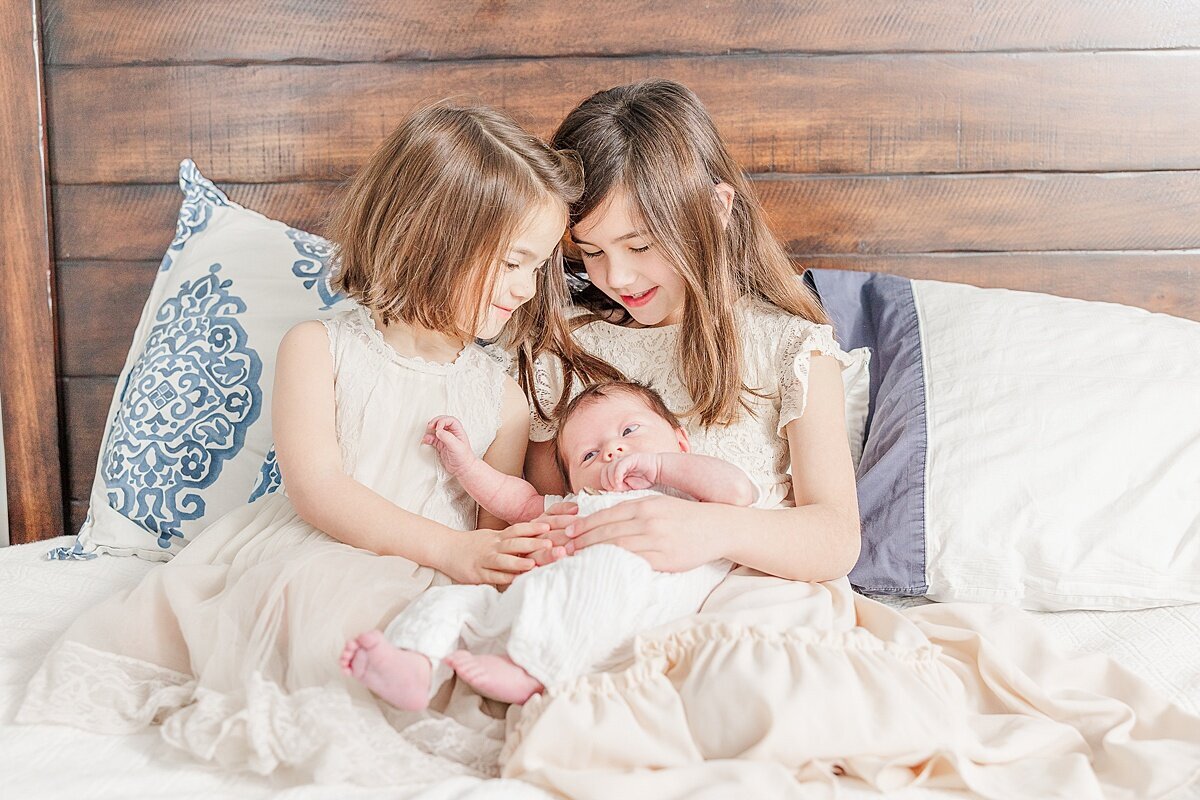 siblings hold baby dung in-home newborn photo session with Sara Sniderman Photography in Needham Massachusetts
