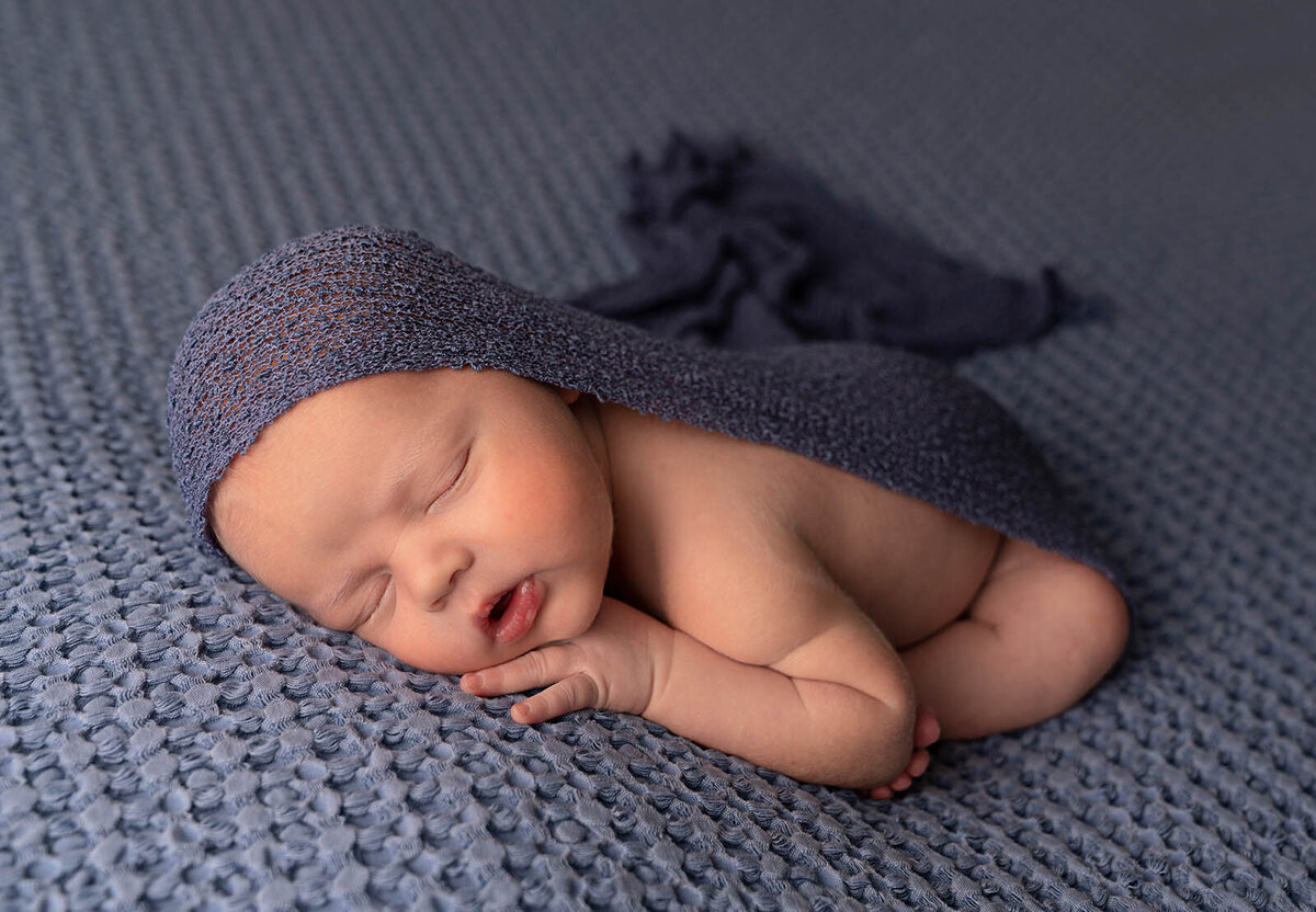 Newborn sleeping on a blue wool blanket