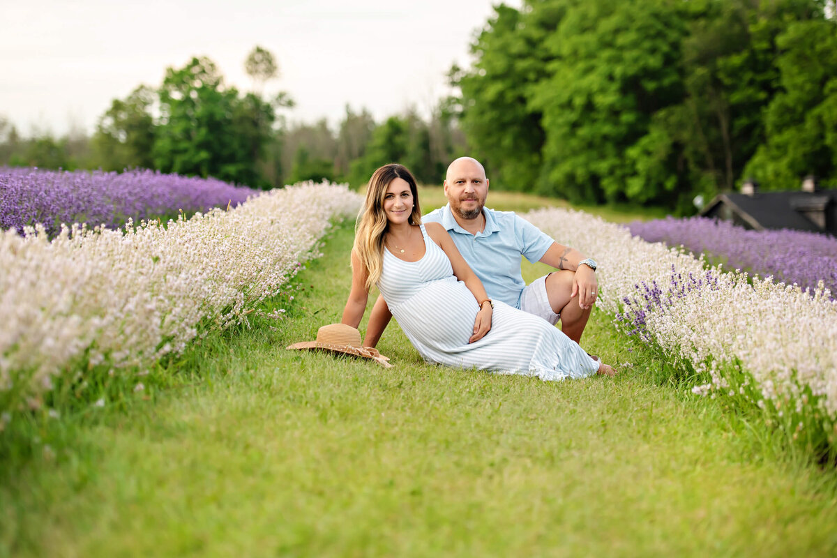 husband and wife sitting on the ground for their outdoor maternity photography session in Burlington, ON