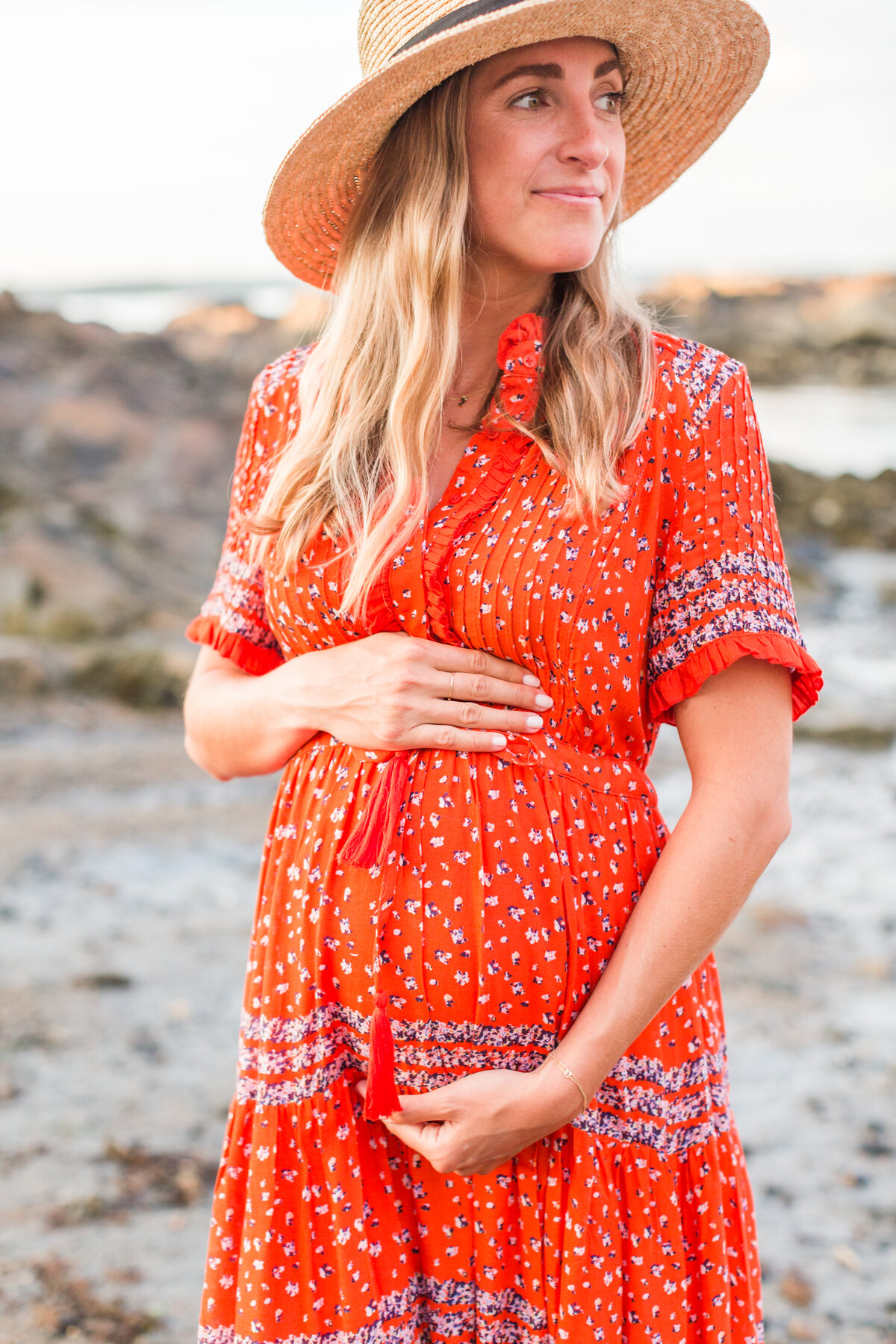 Glowing mom to be wearing straw hat on beach