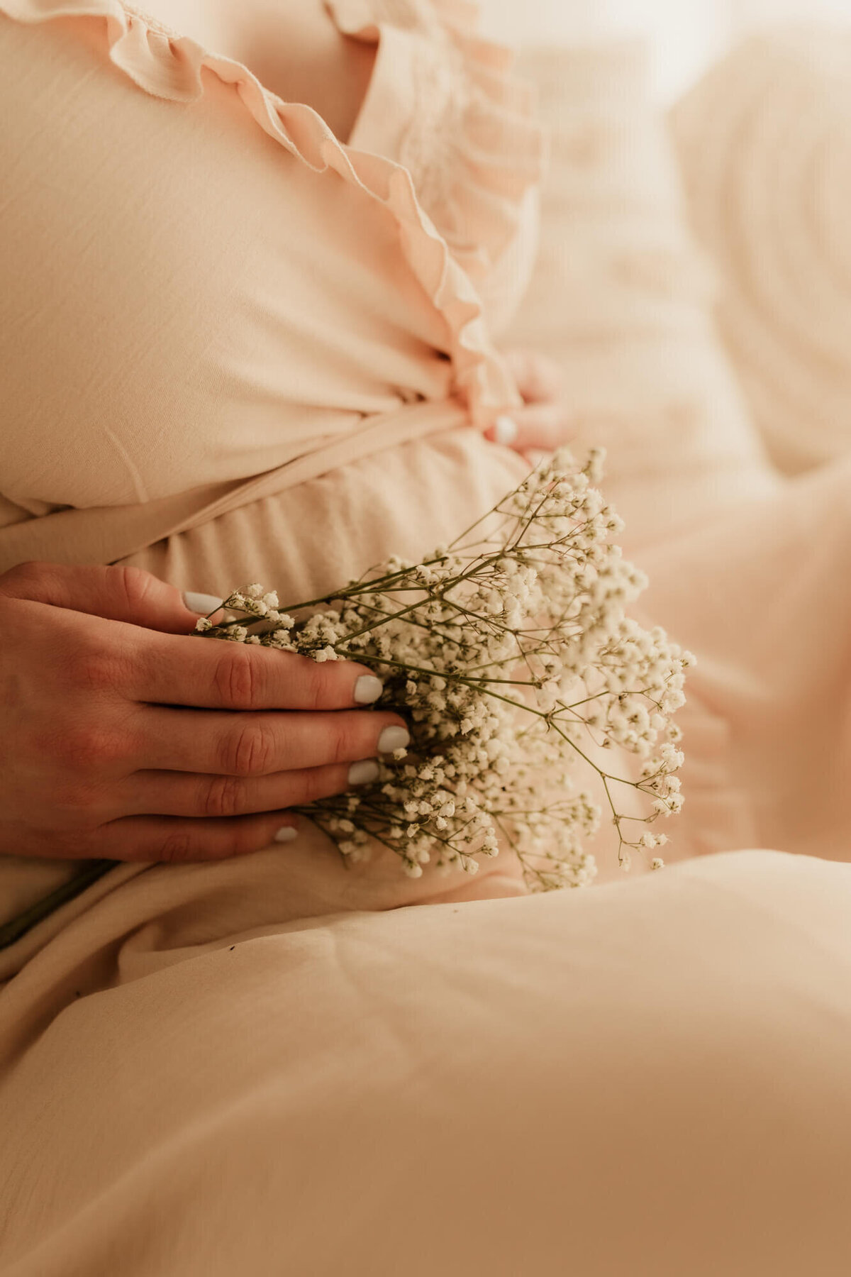 Maternity photo of mother holding baby's breath  flowers near her baby bump