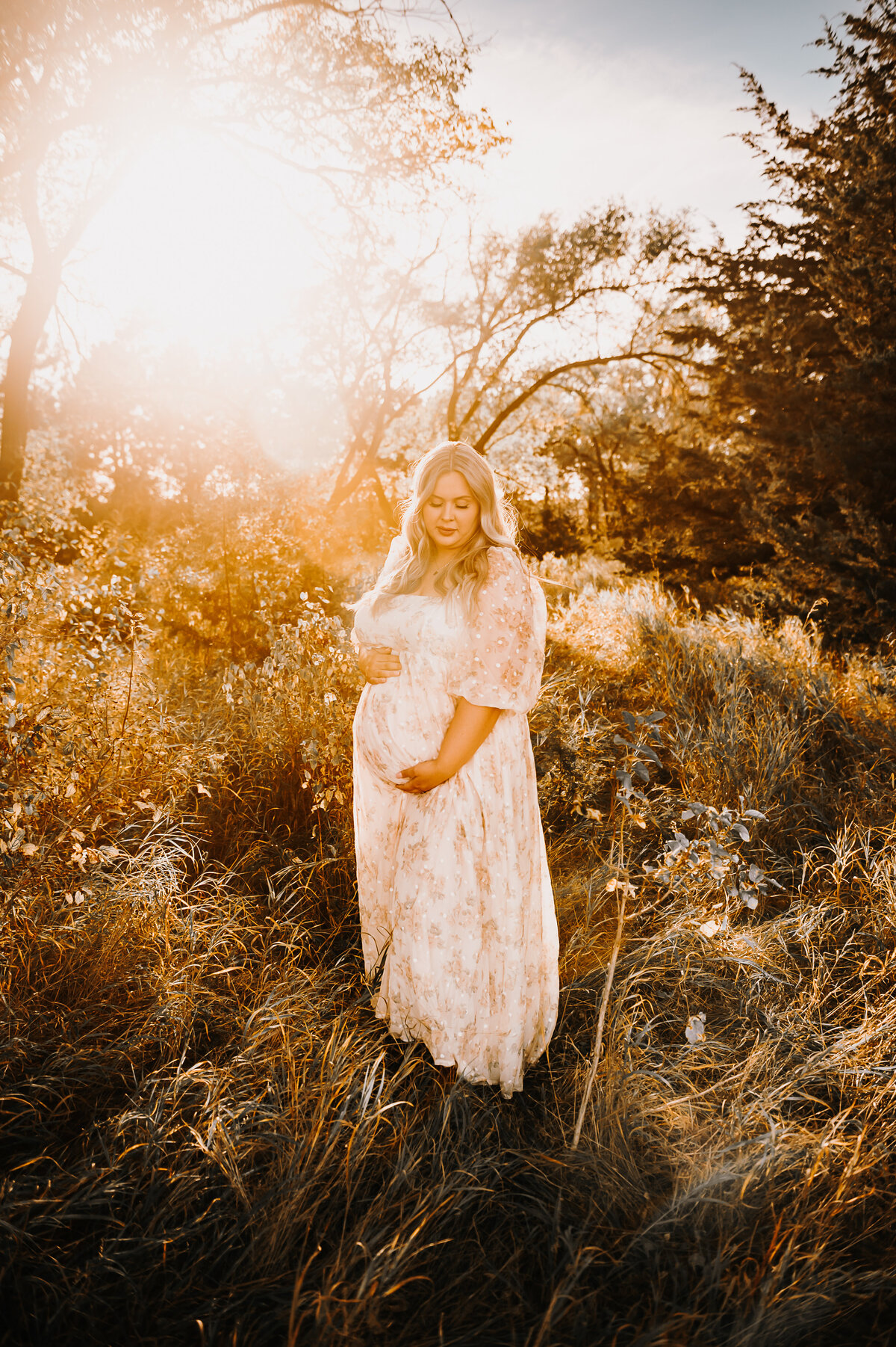 A momma to be is glowing during a maternity shoot near sweet briar lake near bismarck, nd at sunset.
