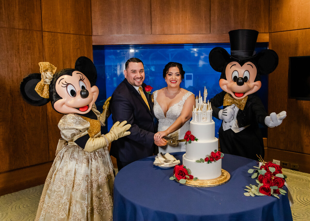 Disney fairytale wedding with Mickey and Minnie and bride and groom cutting the wedding cake