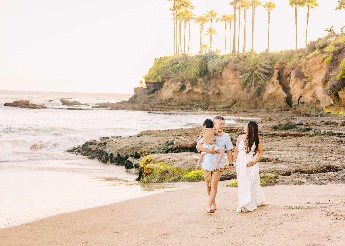 Family walking holding hands during beach maternity session in Laguna Beach.