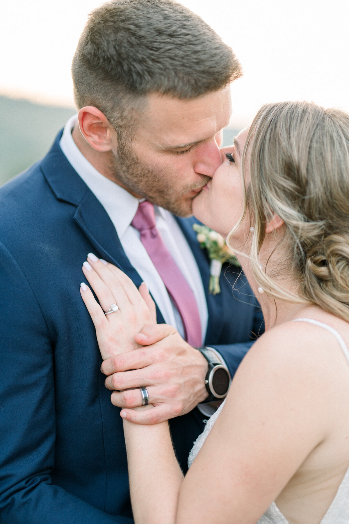 Bride and groom kissing with hands crossed to show wedding rings captured by Niagara wedding photographer