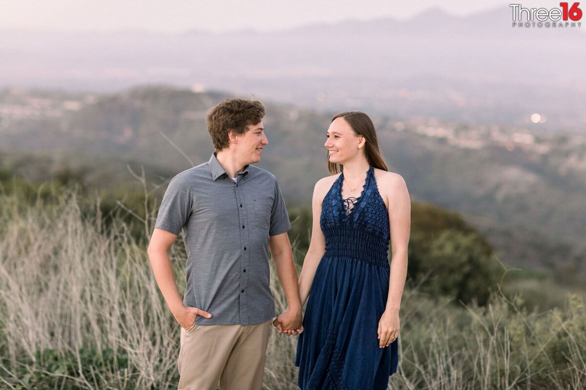 With the valley behind them engaged couple look at one another during photo shoot