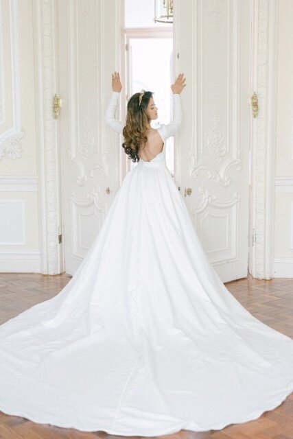 Bride in her dress holding on to the door looking back over her shoulder
