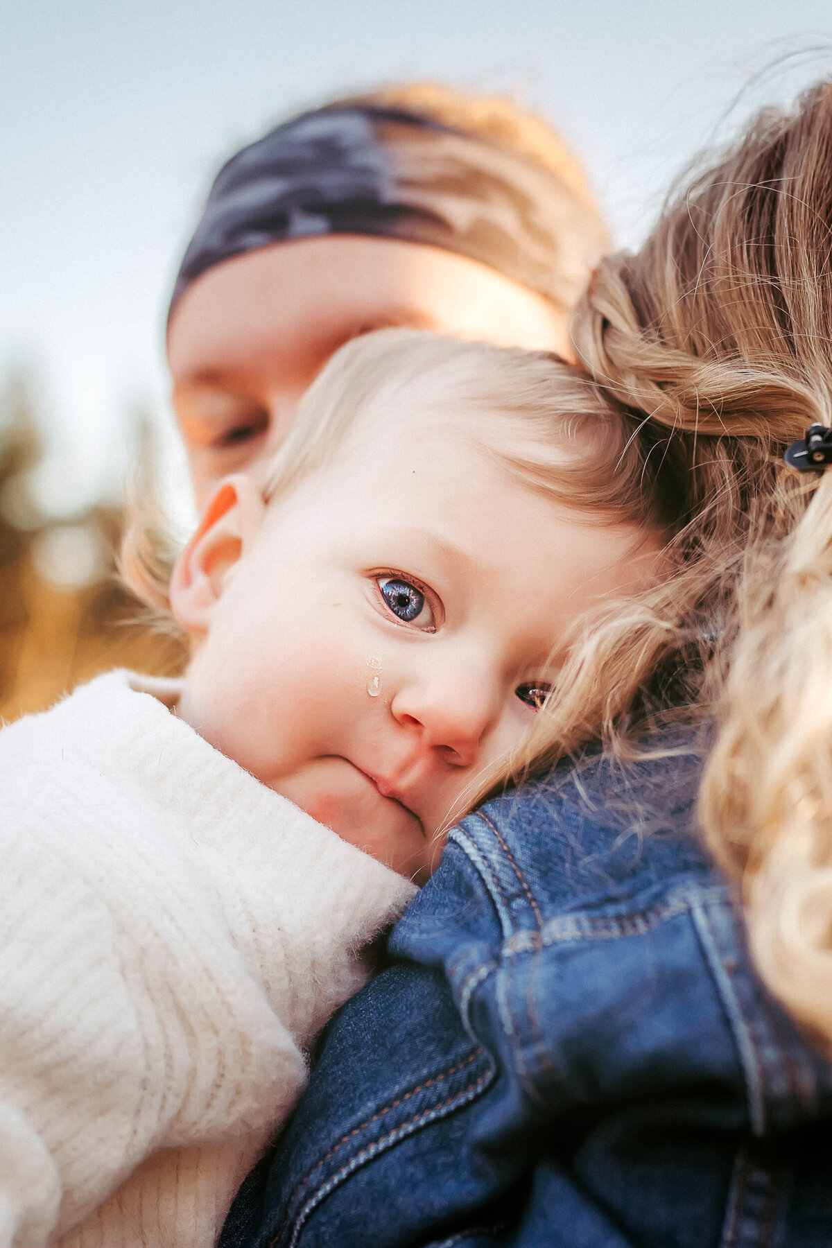 Emotional moment as a baby cries on her sister’s shoulder at Clark Lake Park in Kent, WA, capturing the tenderness of sibling connection.
