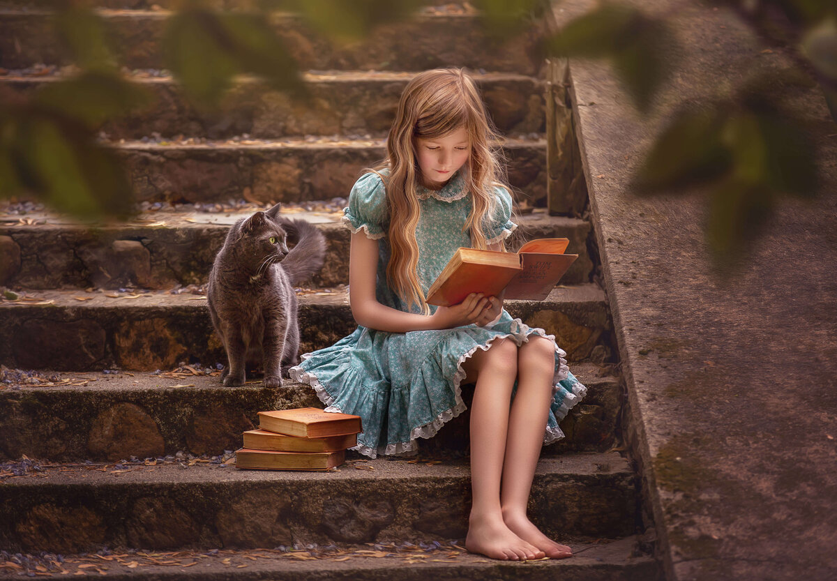 Girl sitting outside on steps with her cat and reading