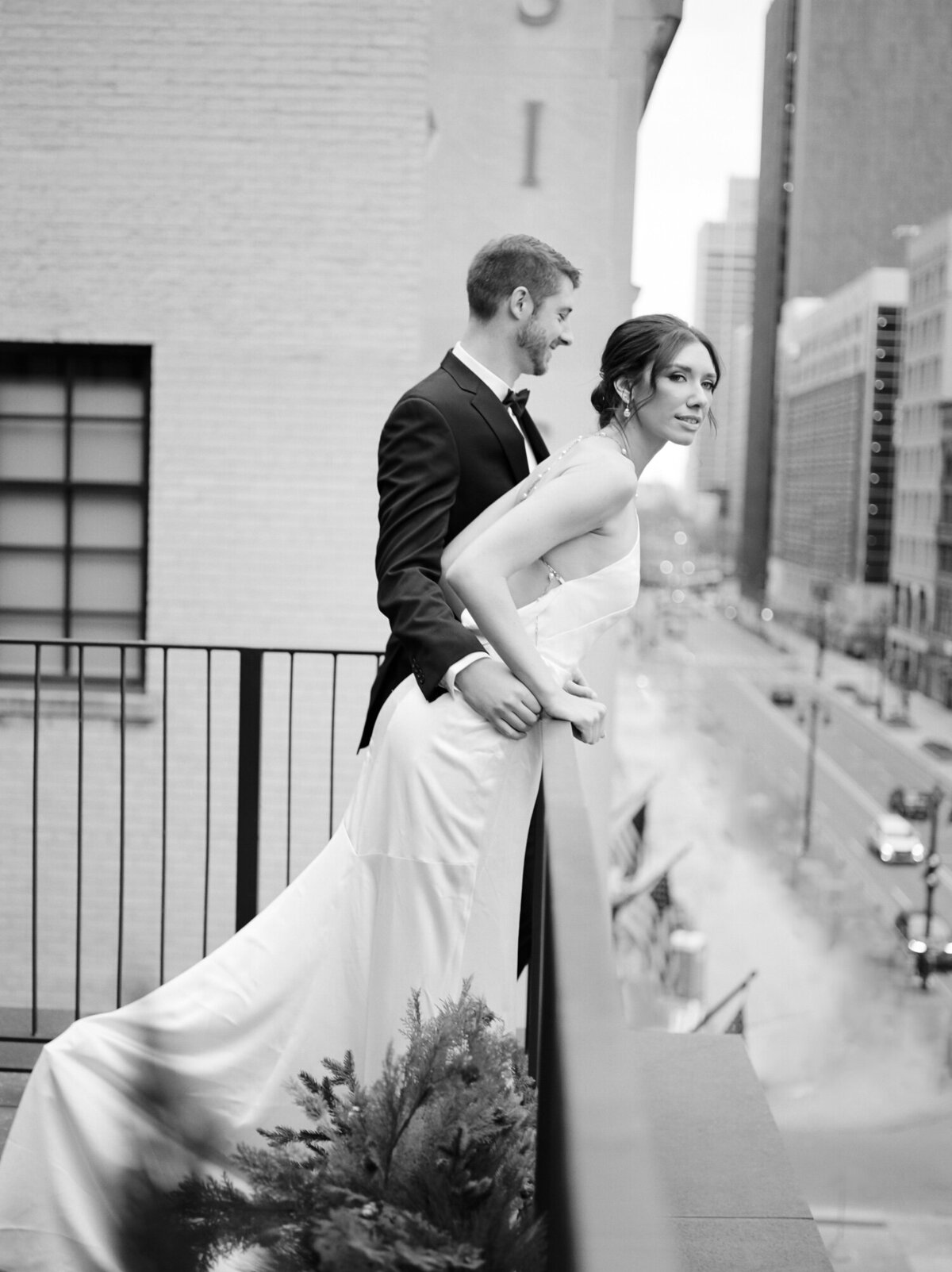 groom, bride leans over balcony of Shinola Hotel, backless pearl wedding dress