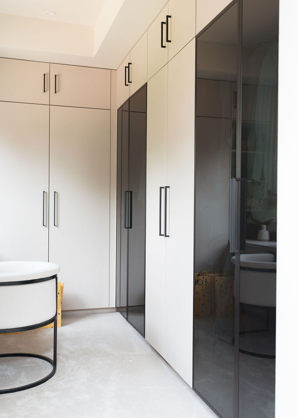 A modern, light-filled walk-in closet with alternating black and white cabinets.