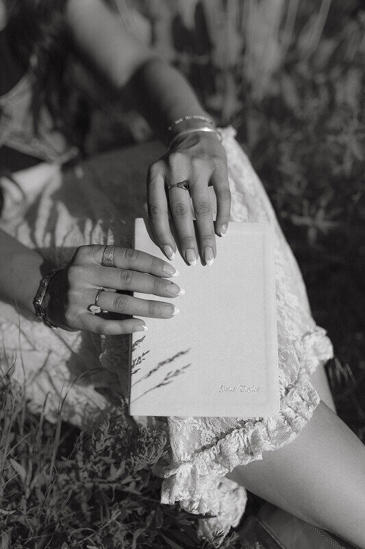 Black and white close up photo of a woman holding a custom Book of Mormon. She is taking missionary portrait photos before she leaves on her mission.