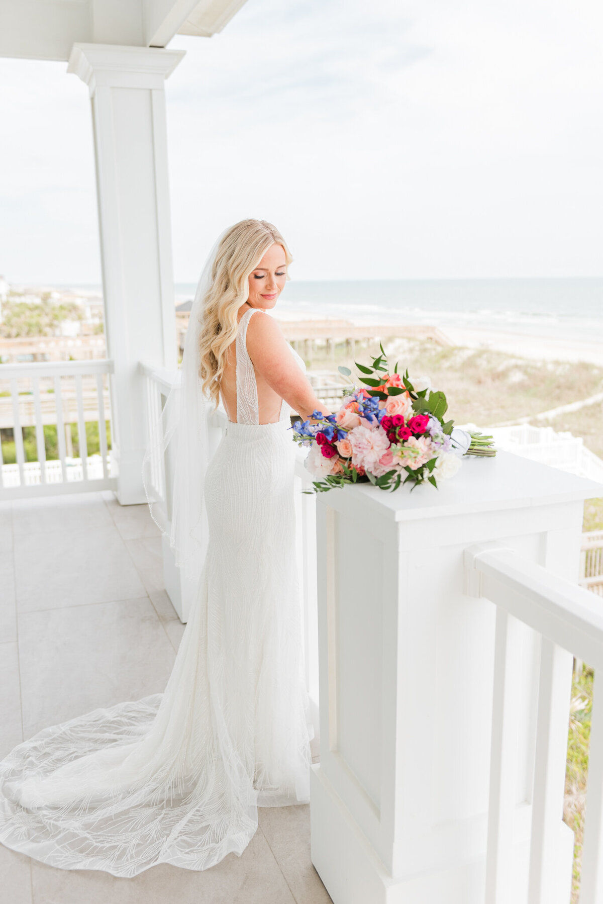 bride looking over balcony in wrightsville beach, nc in her wedding dress